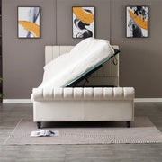 The Ascot Storage Bedframe, in cream velvet with lift-up storage and raised mattress revealing space beneath, stands on a gray rug with a book; three abstract paintings hang on the wall behind.