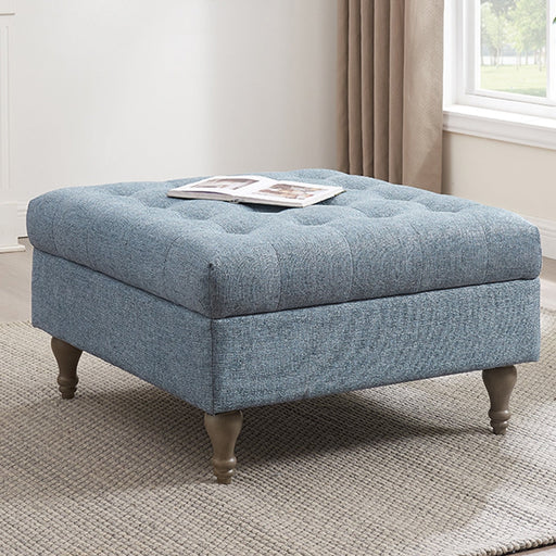 An Abbott Button Top Storage Ottoman in blue, with tufted design and wooden legs, placed on a rug in a room setting.