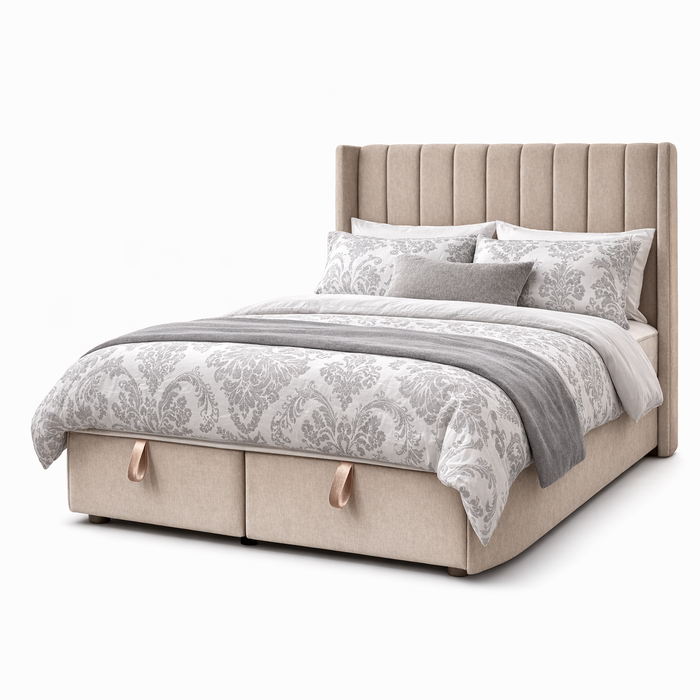 The Hilton Storage Bedframe features a tall, vertically paneled winged headboard in beige upholstery, patterned gray and white bedding, multiple pillows, a gray throw, and two base storage drawers with fabric handles.