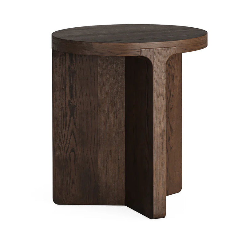 A modern round coffee table made of dark oak with a brush finished texture and subtle brass plates on the sides.