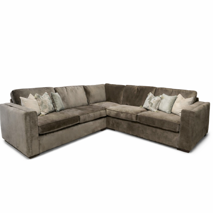 The Ariya is a spacious L-shaped corner sofa for your living room, featuring wide arms, deep seats, brown fabric upholstery, and neutral-tone decorative throw pillows for maximum comfort.