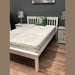 Classic white wooden bed frame with slatted headboard, shown with a mattress and two grey nightstands.