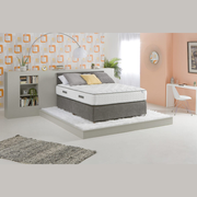 A King Koil Paradise mattress displayed in a modern bedroom setting, showing the top surface with pillows on it, encased in a gray and white cover.