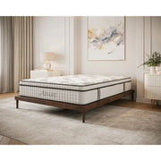 A modern bedroom with a neatly made bed featuring the medium to firm Adare Mattress on a wooden frame, beige carpet, light curtains, a nightstand with a lamp, and abstract wall art.