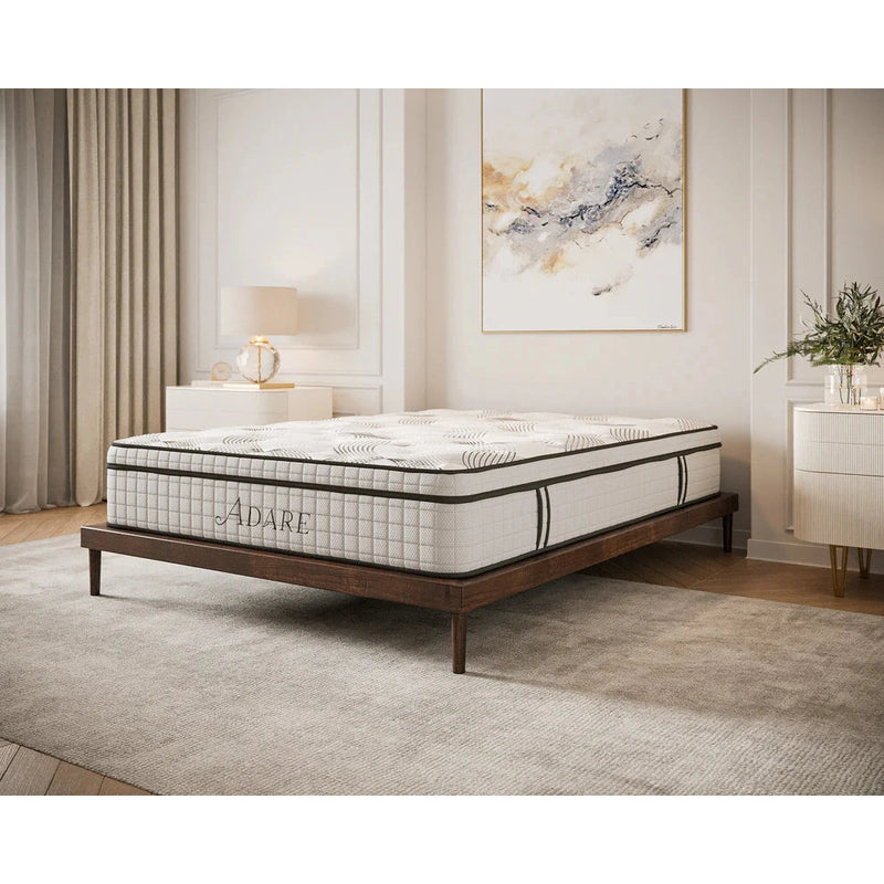A modern bedroom with a neatly made bed featuring the medium to firm Adare Mattress on a wooden frame, beige carpet, light curtains, a nightstand with a lamp, and abstract wall art.