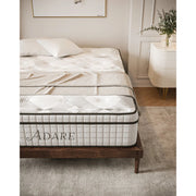 A neatly made bed features the Adare Mattress, known for pocket springs and medium to firm support, on a wooden frame. A nightstand with a vase of greenery and a soft rug complete the softly lit, modern bedroom.