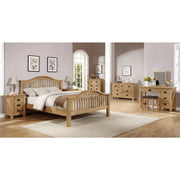 A spacious bedroom featuring the timeless Saoirse Bedframe with a curved headboard, complemented by nightstands, dressers, a vanity, pale walls, framed art, lamps, a beige rug, and large windows for an inviting atmosphere.
