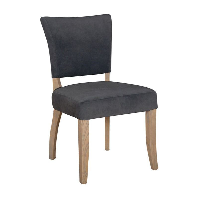 The Duke Dining Chair features a wide, cushioned dark gray velvet washable seat and backrest, light oak wood legs, and a simple, modern design.
