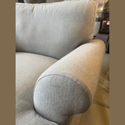 Close-up of a light grey Monroe Sofa Range, highlighting the armrest and backrest in aqua clean fabric. Visible texture, with additional furniture and floor tiles in the background.