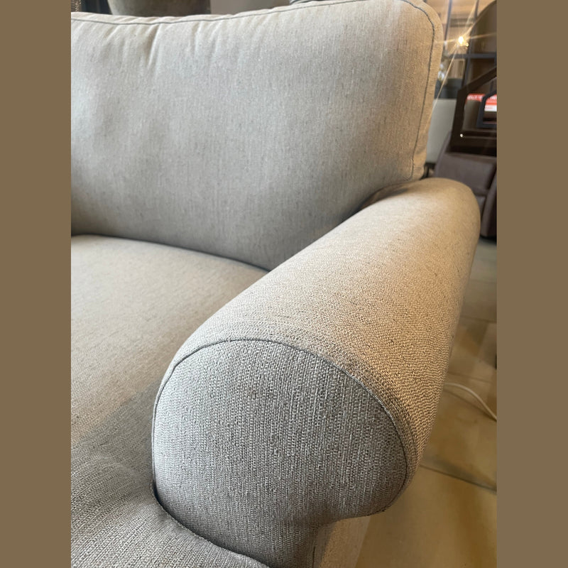 Close-up of a light grey Monroe Sofa Range, highlighting the armrest and backrest in aqua clean fabric. Visible texture, with additional furniture and floor tiles in the background.