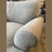 Close-up of a light grey Monroe Sofa Range, highlighting the armrest and backrest in aqua clean fabric. Visible texture, with additional furniture and floor tiles in the background.