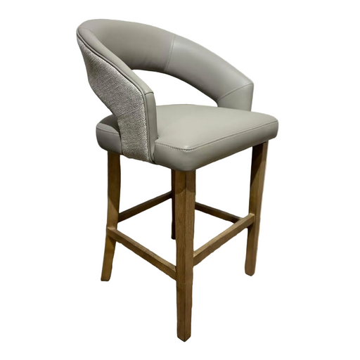 The Willow Counter Stool features a wooden base, light gray cushioned seat, curved backrest with fabric detailing, and an open lower back design. Its clean lines create a contemporary look ideal for modern dining spaces.