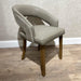 The Willow Dining Chair showcases a curved back, light gray upholstered seat and backrest, and wooden legs, offering modern style ideal for dining spaces with light wood flooring and a textured beige wall backdrop.