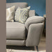 The Chloe Corner Group showcases modern style with its light gray fabric, two patterned throw pillows, soft cushions, and slightly angled armrest, set against a blue wall on a wooden floor for a cozy, contemporary look.