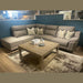 L-shaped taupe or grey leather couch with patterned throw pillows and wood coffee table.