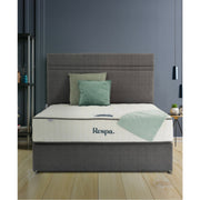 A modern bedroom with a grey upholstered bed, green and grey cushions, a Respa Ashford Mattress with Sleepfresh technology, a light green throw, minimalist decor, dark grey walls, and wooden flooring.