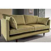 The Hugo sofa, a modern olive green velvet piece with white piping, features two seat and back cushions, two side pillows, wooden legs, and is crafted from durable Aquaclean fabric for easy maintenance.