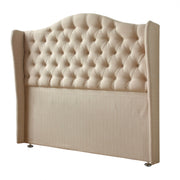 The Respa Miranda headboard features beige upholstery, deep button tufting in a diamond pattern, a curved top edge, winged sides, and stands on small metallic legs against a white background.
