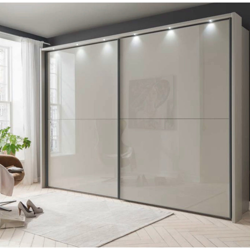 A modern gray sliderobe with clear glass panels and metal frame, located in a bright room with a window and minimalist decor.