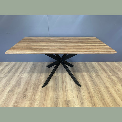 Wooden table with black metal legs against a blue wall.