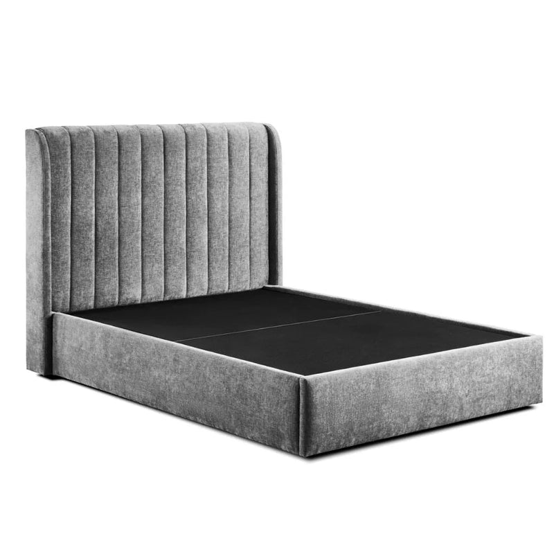 The Frida Storage Bed is a modern gray upholstered frame featuring a tall, vertically-channeled headboard and under-bed storage, pictured without a mattress against a white background.