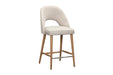 The Florence Counter Stool features a light beige upholstered seat and backrest, an open lower back, wooden legs, and a metal footrest, shown against a white background.