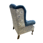 The Queen Anne Chair features blue velvet upholstery on the seat and arms, a cream back and sides with dark floral patterns, and elegant wooden cabriole legs for a classic touch.
