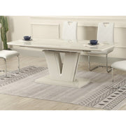 A modern dining room features the vendor-unknown Vicenza table with a V-shaped base, butterfly extension, and six cushioned white chairs with chrome legs on a patterned gray rug; two place settings are on the table.