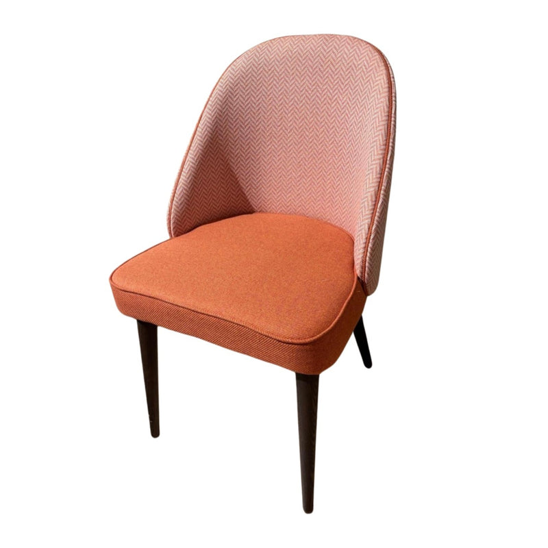 The Slim dining chair features dark wooden legs, an orange cushioned seat, and a pink chevron-patterned backrest. Custom made, this elegant chair blends modern design and comfort, displayed on a white background.