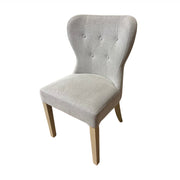The Jacob chair features light grey upholstery, a curved button-tufted backrest, and elegant grey washed wood legs, displayed against a white background.