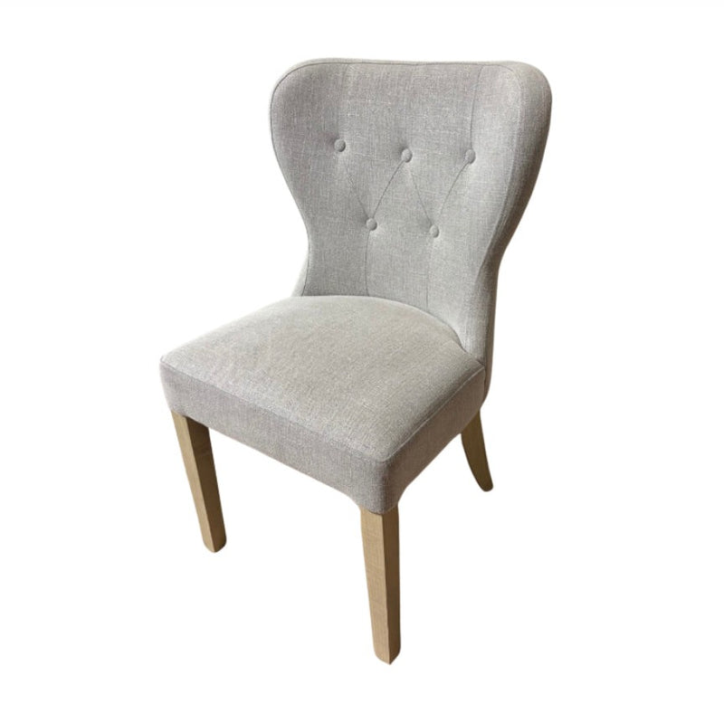 The Jacob chair features light grey upholstery, a curved button-tufted backrest, and elegant grey washed wood legs, displayed against a white background.