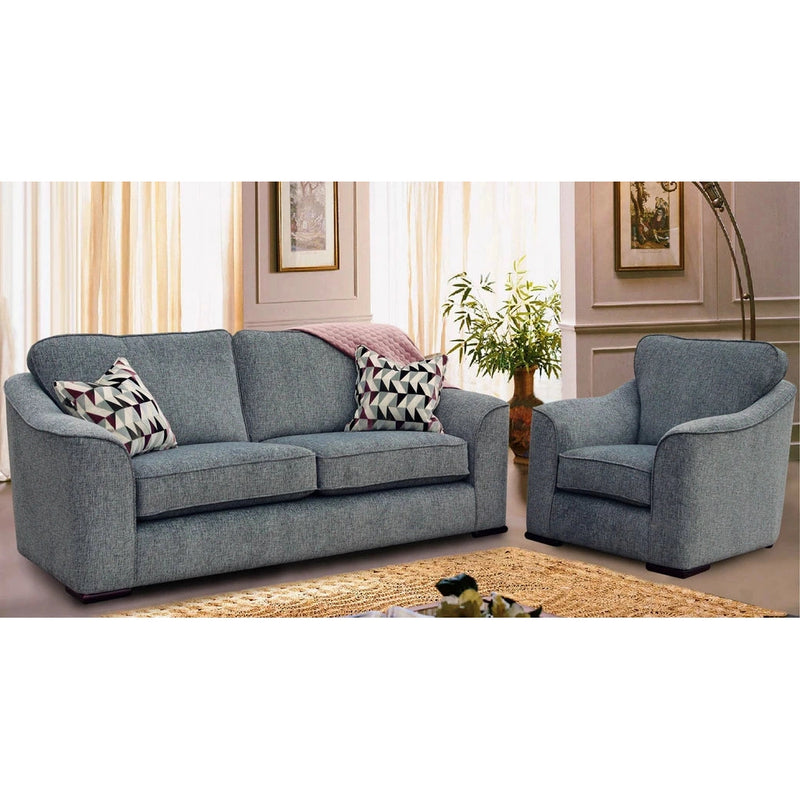 A modern living room features the Shelly sofa and matching armchair by vendor-unknown, both in gray aquaclean fabric with curved armrests. Two patterned pillows sit on the sofa. Light curtains, framed wall art, and a plant complete the background.