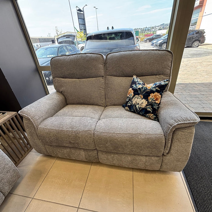 A Barrington Electric Recliner with supportive cushioning and a single floral-patterned throw pillow sits near large windows in a showroom with cars visible outside.