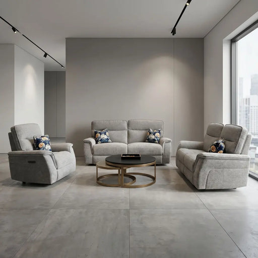 Spacious modern living room featuring Barrington Electric Recliner in durable upholstery, paired with light gray sofas, floral pillows, round wooden coffee table, large city-view window, and minimalistic neutral decor.