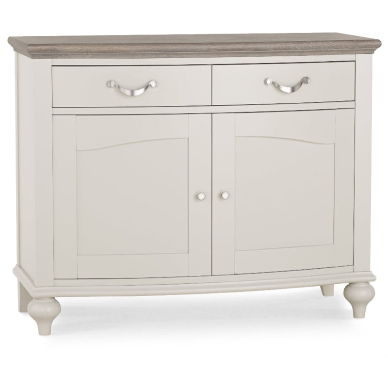 The Montreux Small Sideboard features a light gray washed oak finish, dark wood top, two drawers with metal handles, two lower cabinet doors with round knobs, and stands on four short legs.