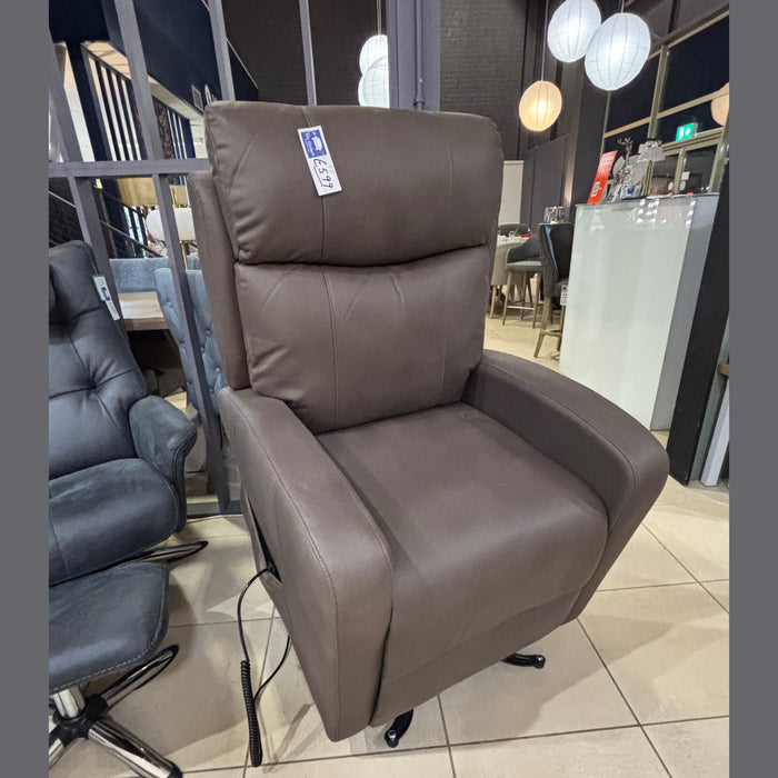The Hugo Lift & Rise, a large brown reclining armchair with twin motors and leg support, is displayed in a furniture store on a tiled floor beside a dark gray chair, with a price tag attached.