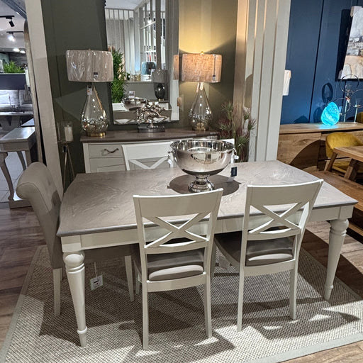 Traditional dining room setup featuring a large arched mirror, silver lamps, and a decorative serving bowl.