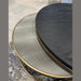 Close-up of the Noir Coffee Table Nest: one table has a textured light metallic top, the other a smooth dark wood surface; both feature gold-colored rims and rest on a gray carpeted floor.