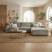 A modern living room featuring the Opus Chaise in Aquaclean fabric, round nesting coffee tables, neutral decor, large arched windows with sheer curtains, indoor plants, a jute rug, and wood accents for natural texture.