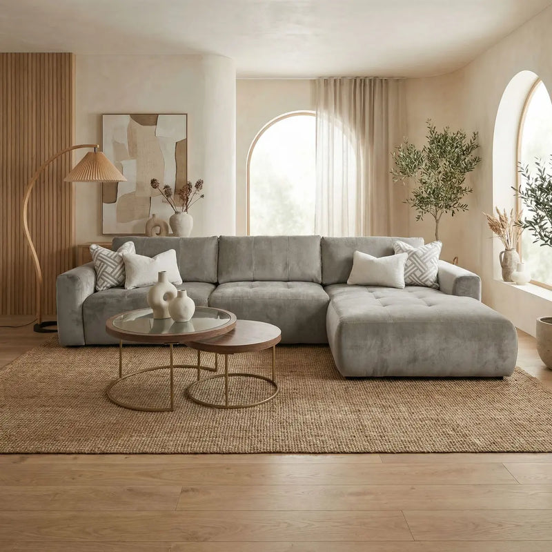 A modern living room featuring the Opus Chaise in Aquaclean fabric, round nesting coffee tables, neutral decor, large arched windows with sheer curtains, indoor plants, a jute rug, and wood accents for natural texture.