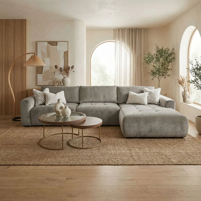 A modern living room featuring the Opus Chaise in Aquaclean fabric, round nesting coffee tables, neutral decor, large arched windows with sheer curtains, indoor plants, a jute rug, and wood accents for natural texture.