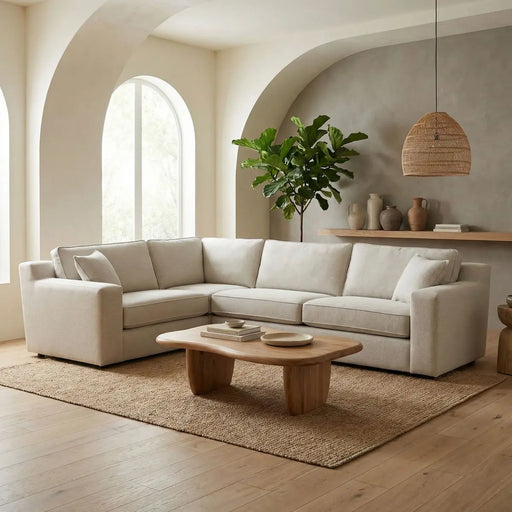 A modern living room featuring the Alice Corner Group in beige aqua clean fabric, a wooden coffee table, jute rug, large potted plant, arched windows, minimalist decor on a floating shelf, and a neutral-toned wall.