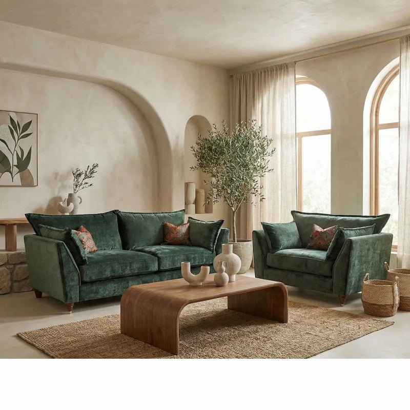 An elegant living room featuring a Cleo Range sofa, wooden coffee table, woven rug, sheer curtains on arched windows, a potted tree, and minimalistic wall art.