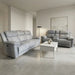 A modern living room features the Elenor Electric Reclining Range in gray chenille fabric, a matching armchair, a white coffee table with ceramic vases, a floor lamp, and abstract wall art. Light walls and a concrete floor complete the contemporary look.