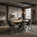 A modern industrial-style meeting room featuring the Dalton 160cm Ext Table & 6 Pedro Chairs, with exposed brick walls, large windows, pendant lights, metal shelves, decorative gears, and a potted plant.