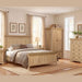A cozy bedroom with light wood Oslo Wardrobe, matching bed, nightstands, and dresser in light oak. Neutral bedding, modern handles, botanical prints, and beige curtains create a warm inviting space.