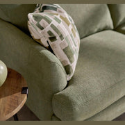 A close-up of the Joni Range sofa in light green with a geometric-patterned cushion in green and white. A round wooden side table features a matching green vase and decor, ideal for modern interiors.