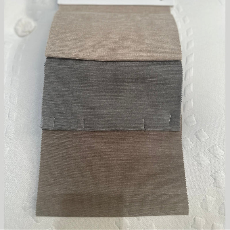 A fabric swatch card labeled REMIND BASE AND HEADBOARD shows three rectangular samples—ideal for selecting upholstery for the Hilton Storage Bedframe—pinned to a white card on a textured white background.