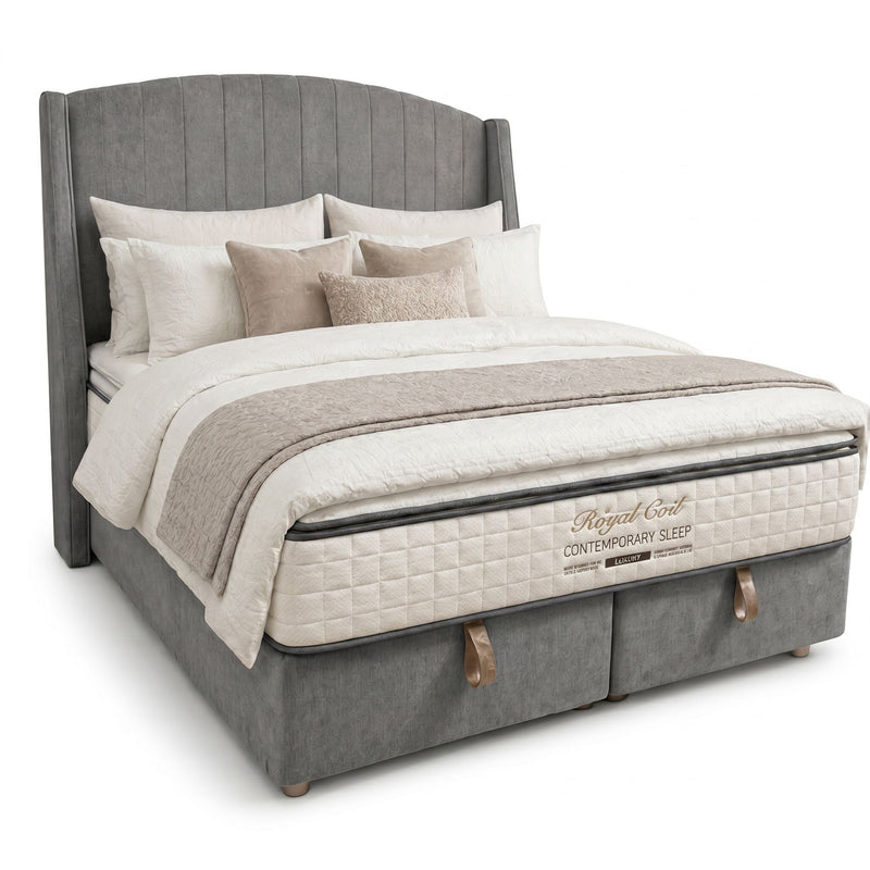 A modern gray Westbury Storage Bedframe with a tall, winged headboard, layered white and beige bedding, several pillows, and a mattress labeled Regal Edit Contemporary Sleep featuring tan side handles.