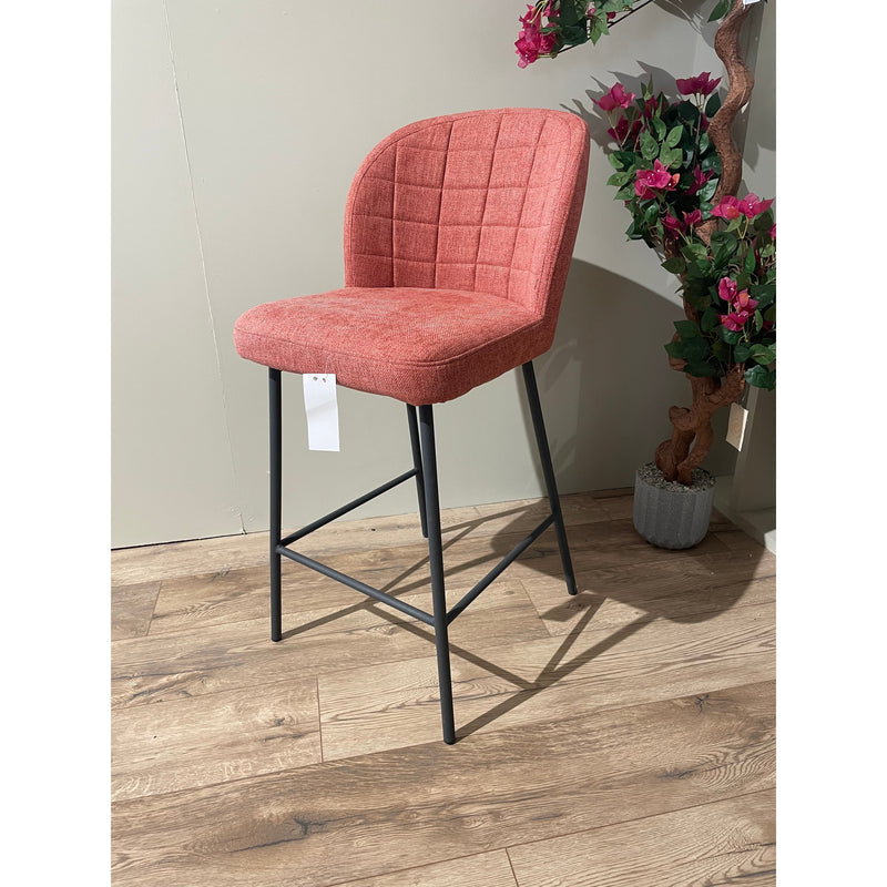 A red upholstered bar stool with a black metal frame and a cushioned top, standing on a wooden floor.